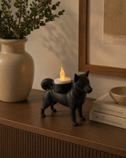 Zwarte Shiba Inu waxinelichthouder met LED-waxinelichtje op donker kastje met decoratie en vaas langs de wand.
